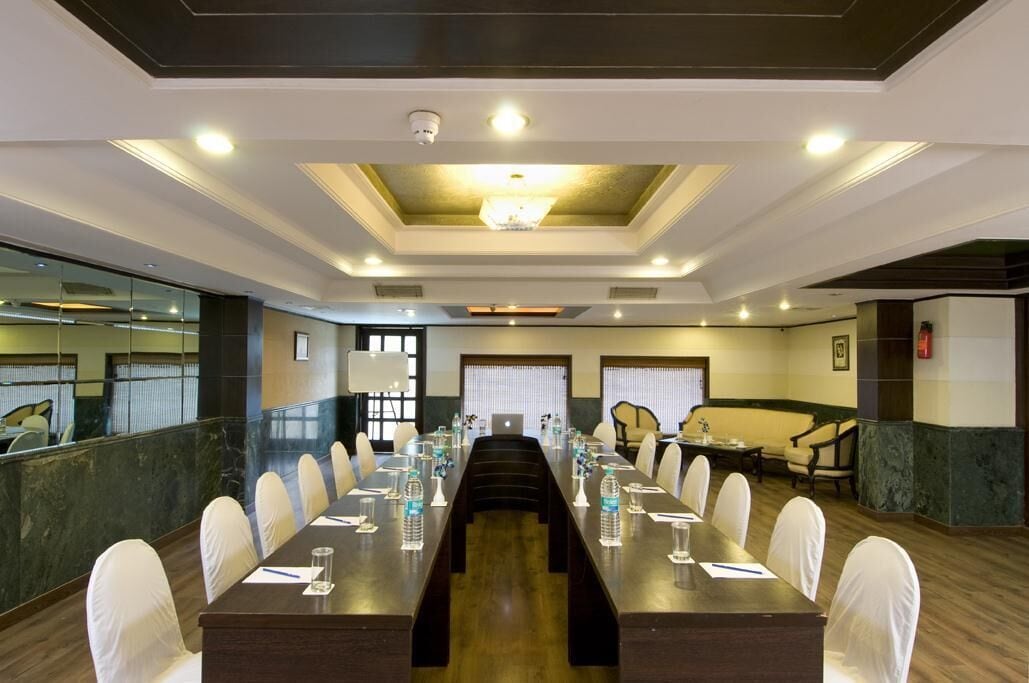 A conference room with a long table, white chairs, and a chandelier.