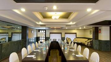 A conference room with a long table, white chairs, and a chandelier.