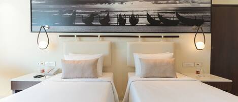 A hotel room with two beds, a large painting of boats on the wall, and bedside lamps.
