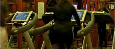 A treadmill area with wooden paneling and a mirror reflecting the space.