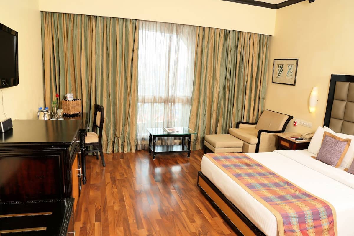 A hotel room with a bed, a desk, a chair, a sofa, and a television.
