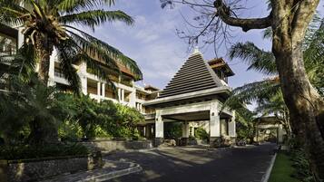 A hotel entrance with a covered walkway, palm trees, and a stone pathway.