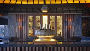 A bar area with a large decorative bowl holding bottles, wooden paneling, and a glass door with a view of bottles inside.