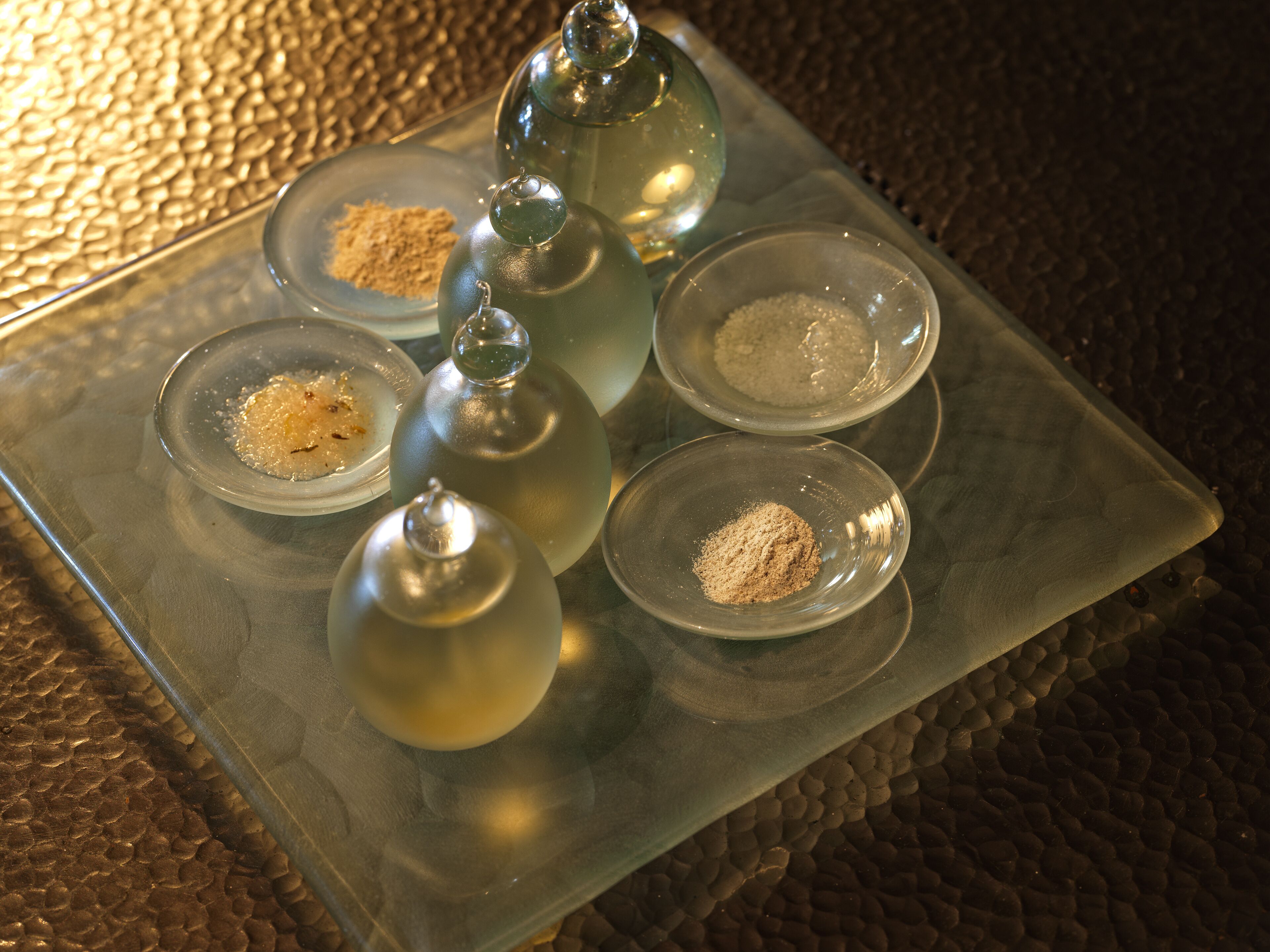 A glass tray with clear glass containers and bowls containing various powders.