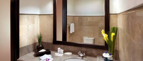 A modern bathroom with a marble sink, a large mirror, and a vase with yellow flowers.