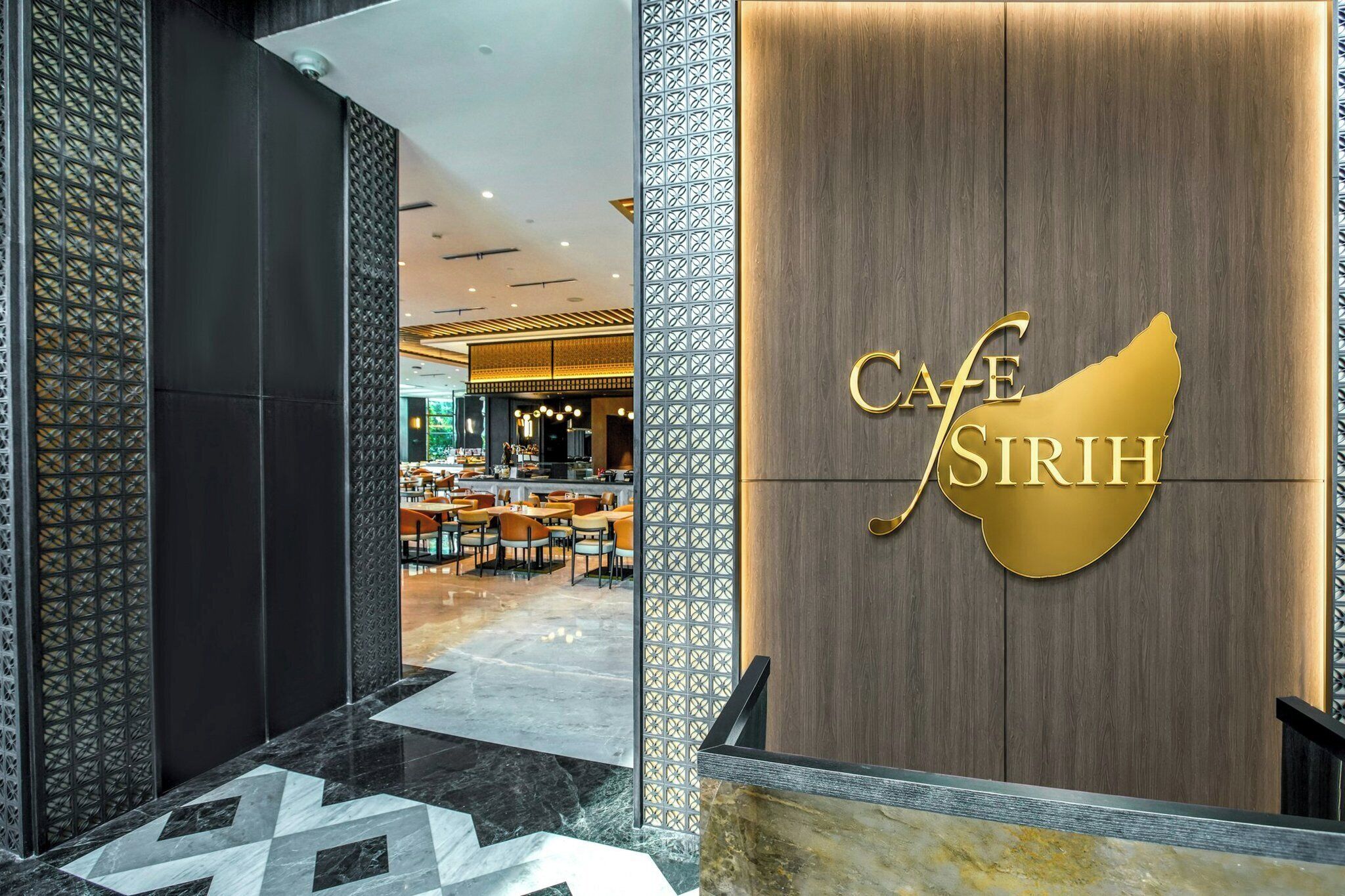 A modern interior with a reception desk, a patterned wall, and a seating area with tables and chairs.