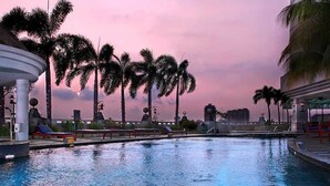 Una piscina con palmeras y un cielo al atardecer.