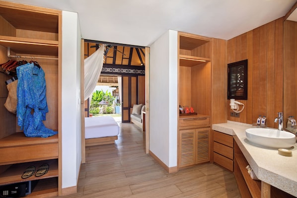 Habitación de hotel con detalles de madera, una cama, baño con lavamanos y vistas al exterior.
