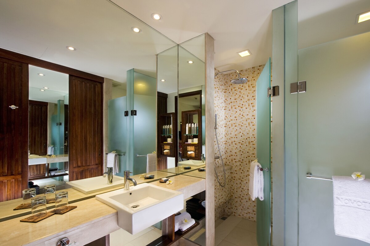 A modern bathroom with two sinks, a large mirror, and a glass shower enclosure.