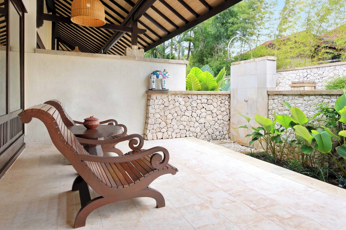 A wooden bench with a table, a stone wall, and a woven basket.