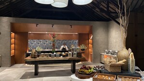 A modern kitchen with a central island, wooden cabinets, and a decorative vase with flowers. - Novotel Bali Benoa (Nusa Dua)