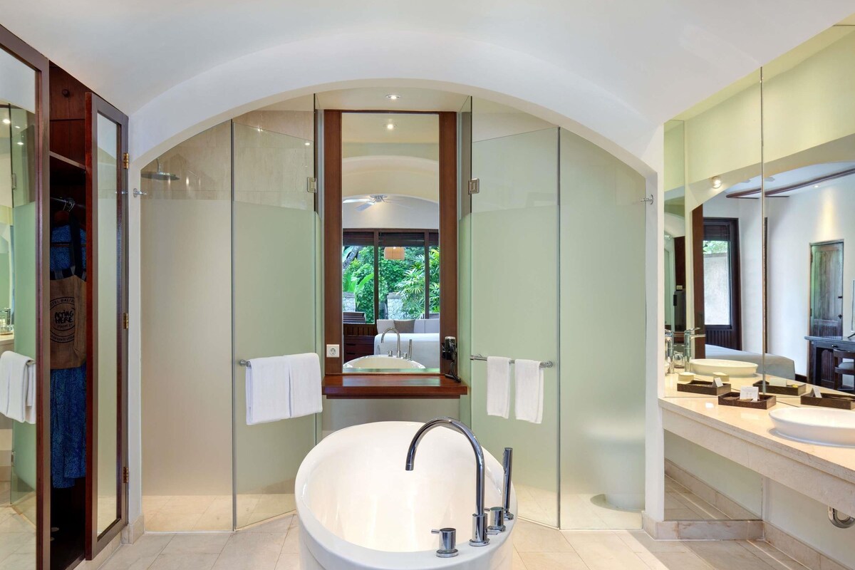 A modern bathroom with a freestanding bathtub, a large mirror, and a glass-enclosed shower area.