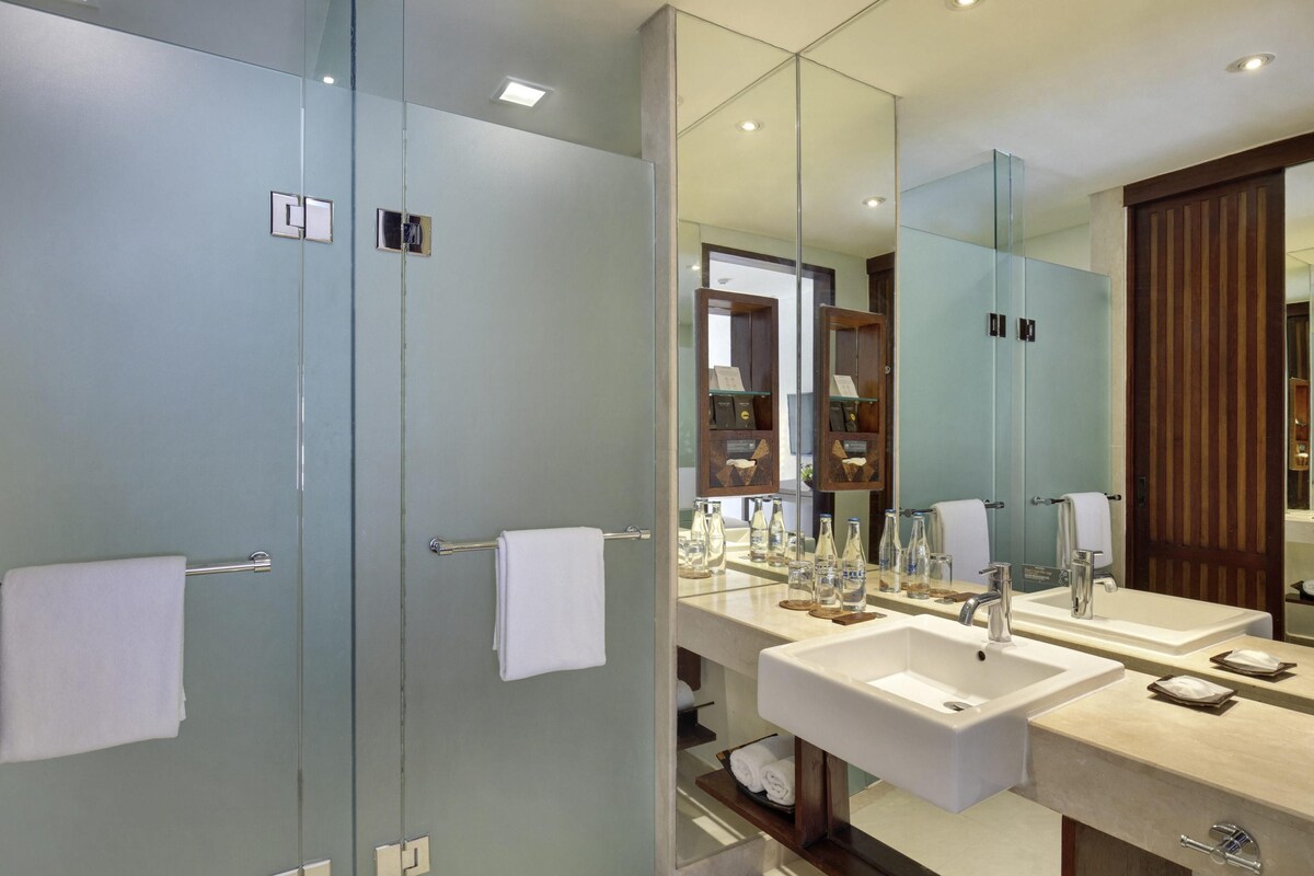 A modern bathroom with two sinks, a large mirror, and a glass shower enclosure.