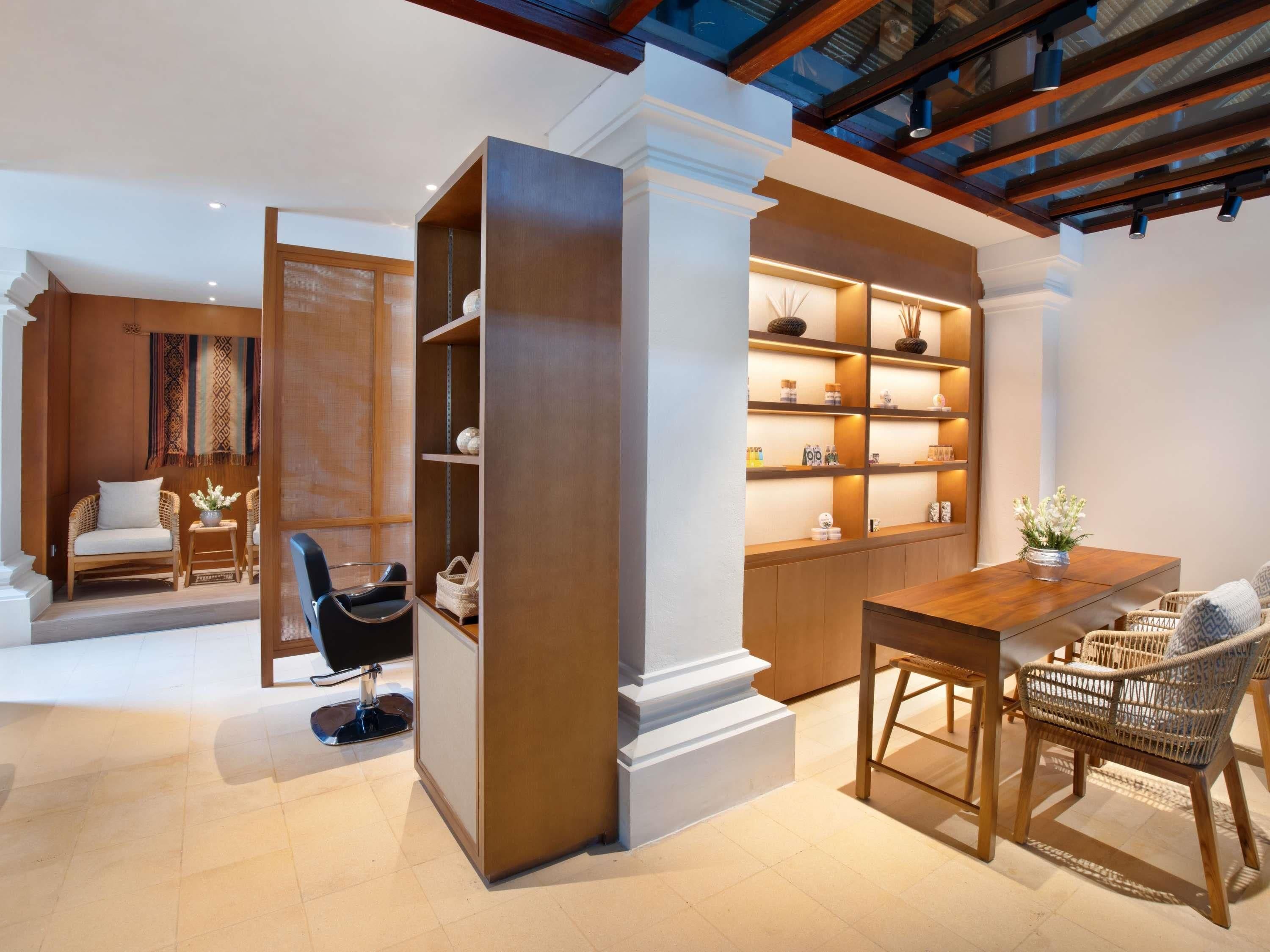 A modern interior with a wooden table, wicker chairs, a bookshelf, and a seating area with a patterned rug.