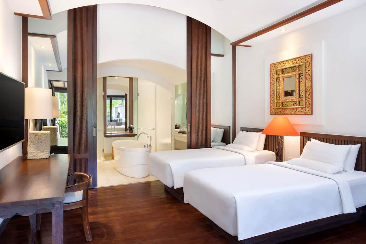 Une chambre d’hôtel avec deux lits, une grande baignoire, une télévision et un bureau en bois.