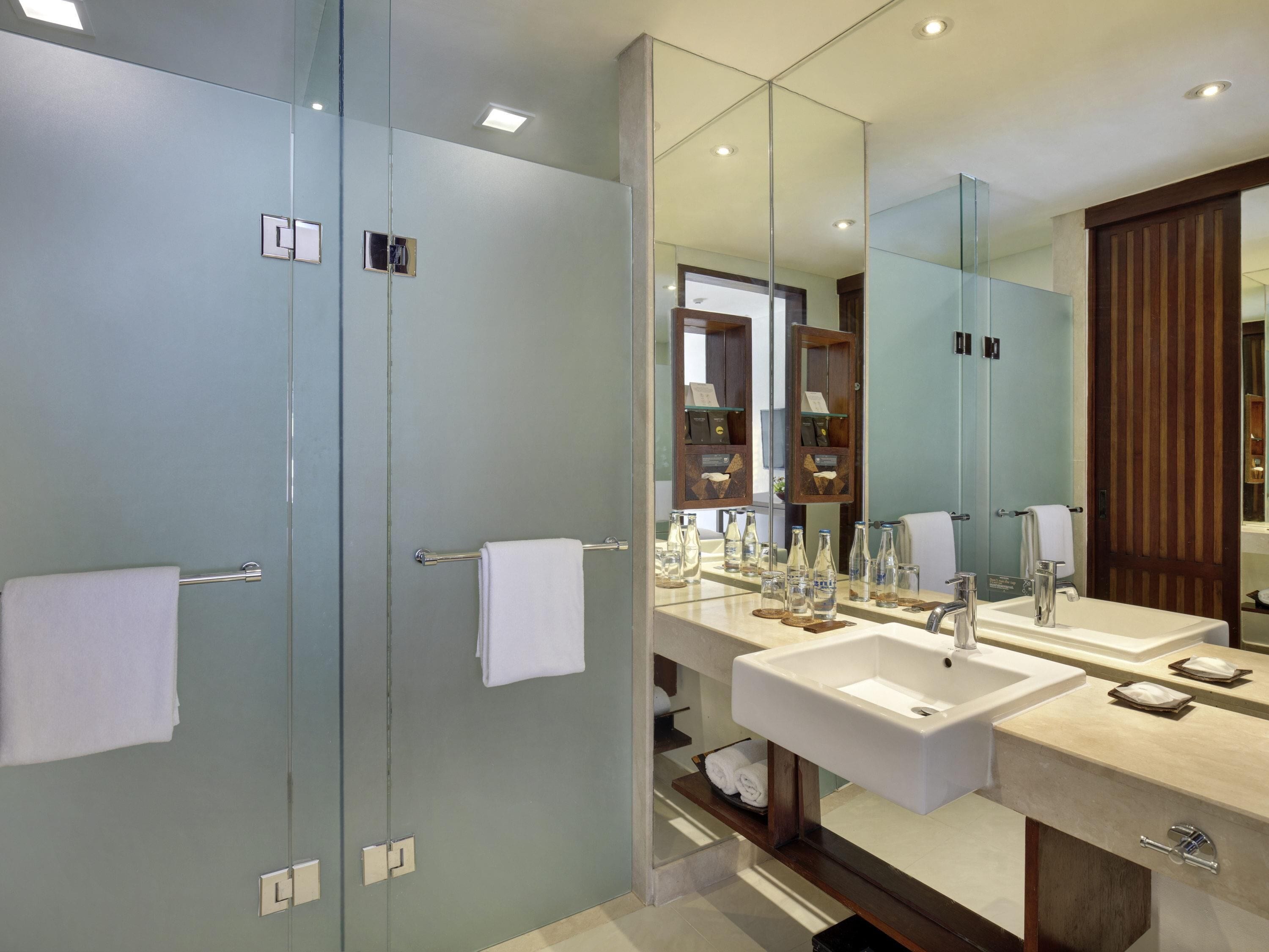A modern bathroom with two sinks, a large mirror, and a glass shower enclosure.