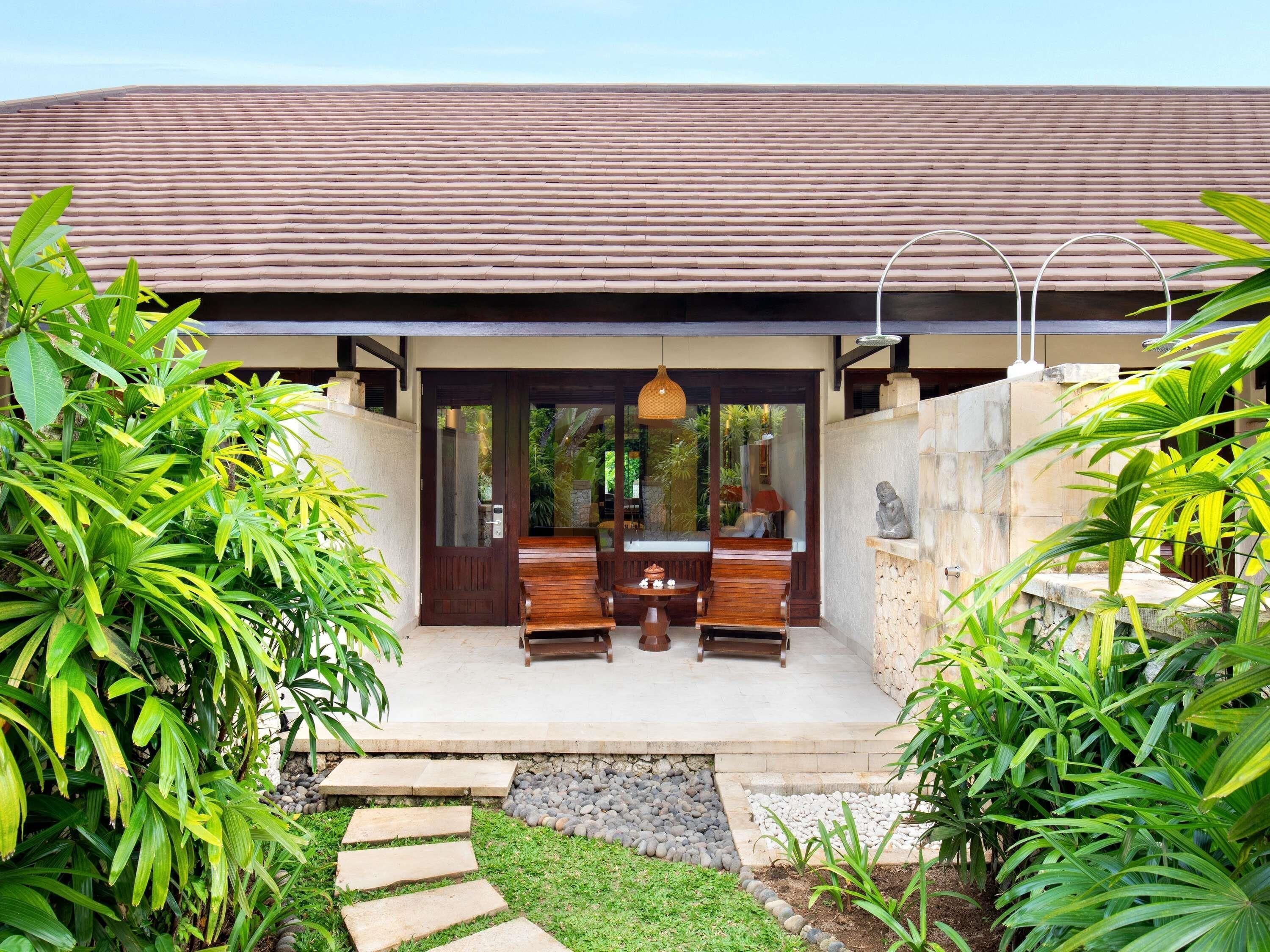 A modern house with a tiled roof, a wooden bench outside, and lush greenery.