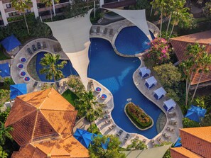 An aerial view of a resort with multiple swimming pools, sun loungers, and palm trees. - Prime Plaza Suites Sanur - Bali (Denpasar)