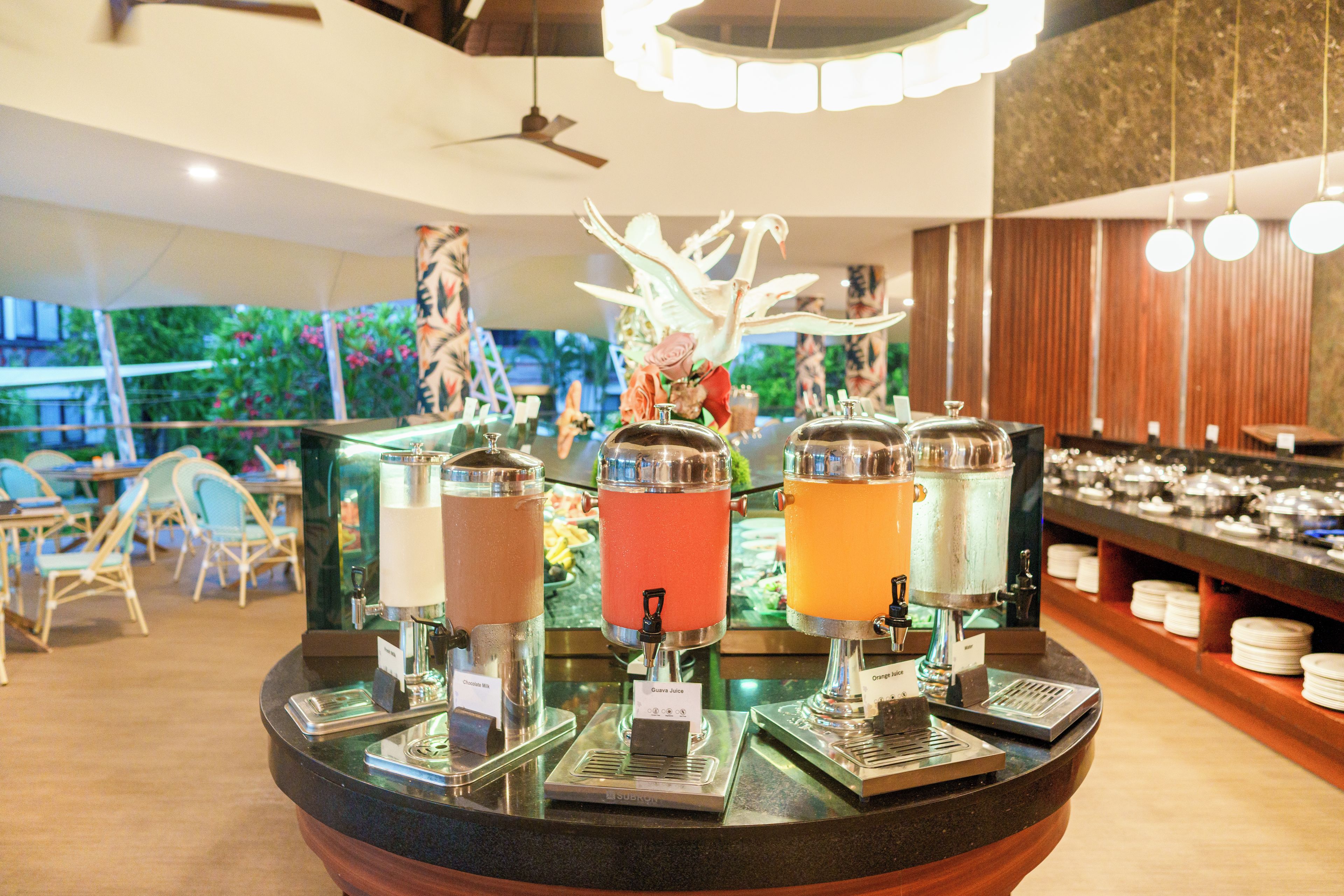 A bar area with multiple beverage dispensers, a ceiling fan, and a view of the outdoors.