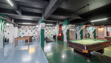 A recreational area with a pool table, foosball table, and a billiards table.