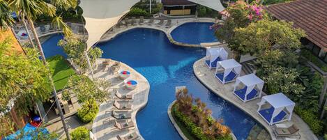 Un resort con varias piscinas, zonas de descanso y un edificio grande al fondo.