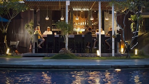 Ein Außenbereich mit Bar, Sitzgelegenheiten und einem Pool im Vordergrund.