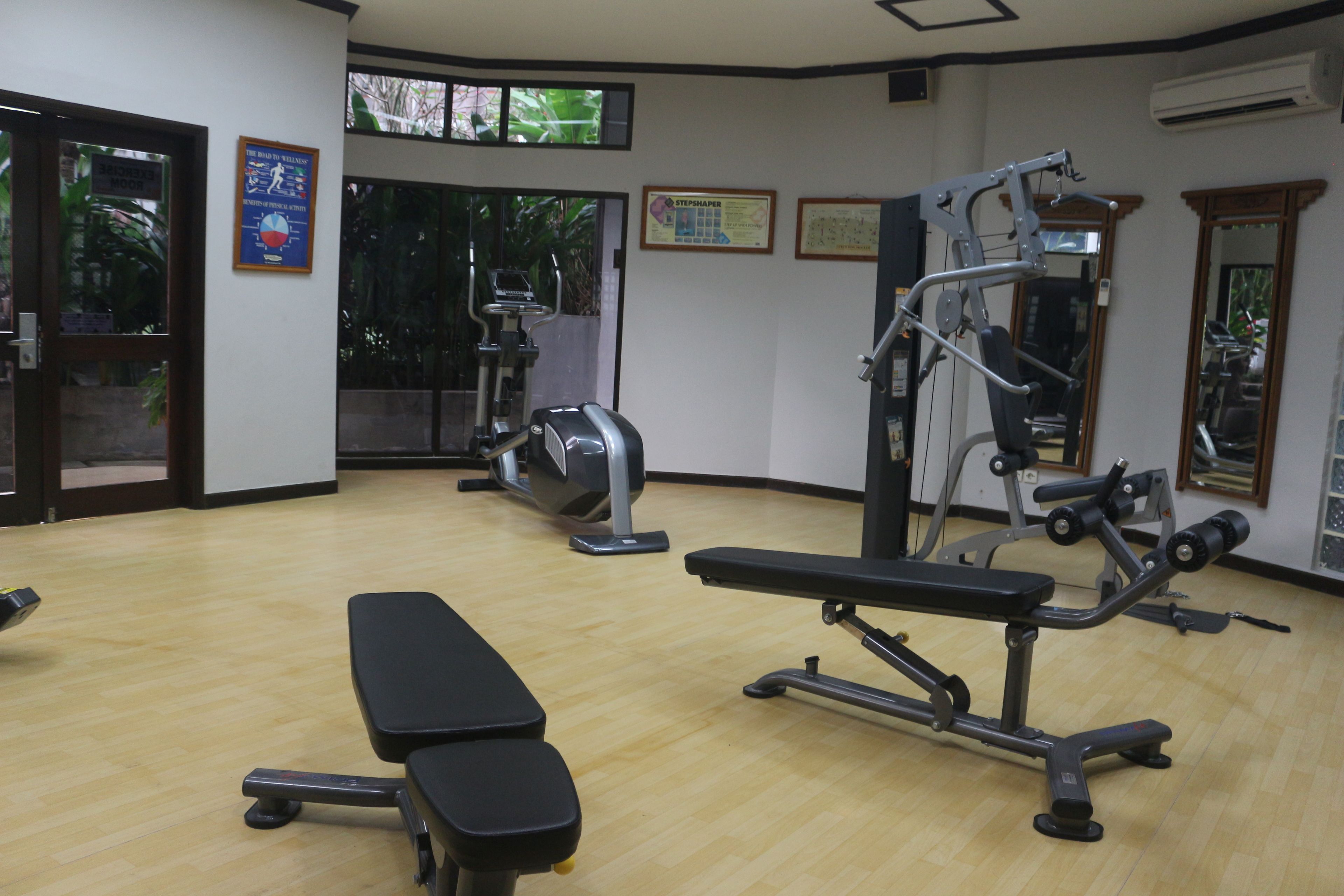 Une salle de sport équipée de matériel d’exercice, d’un banc et d’une porte donnant sur l’extérieur.