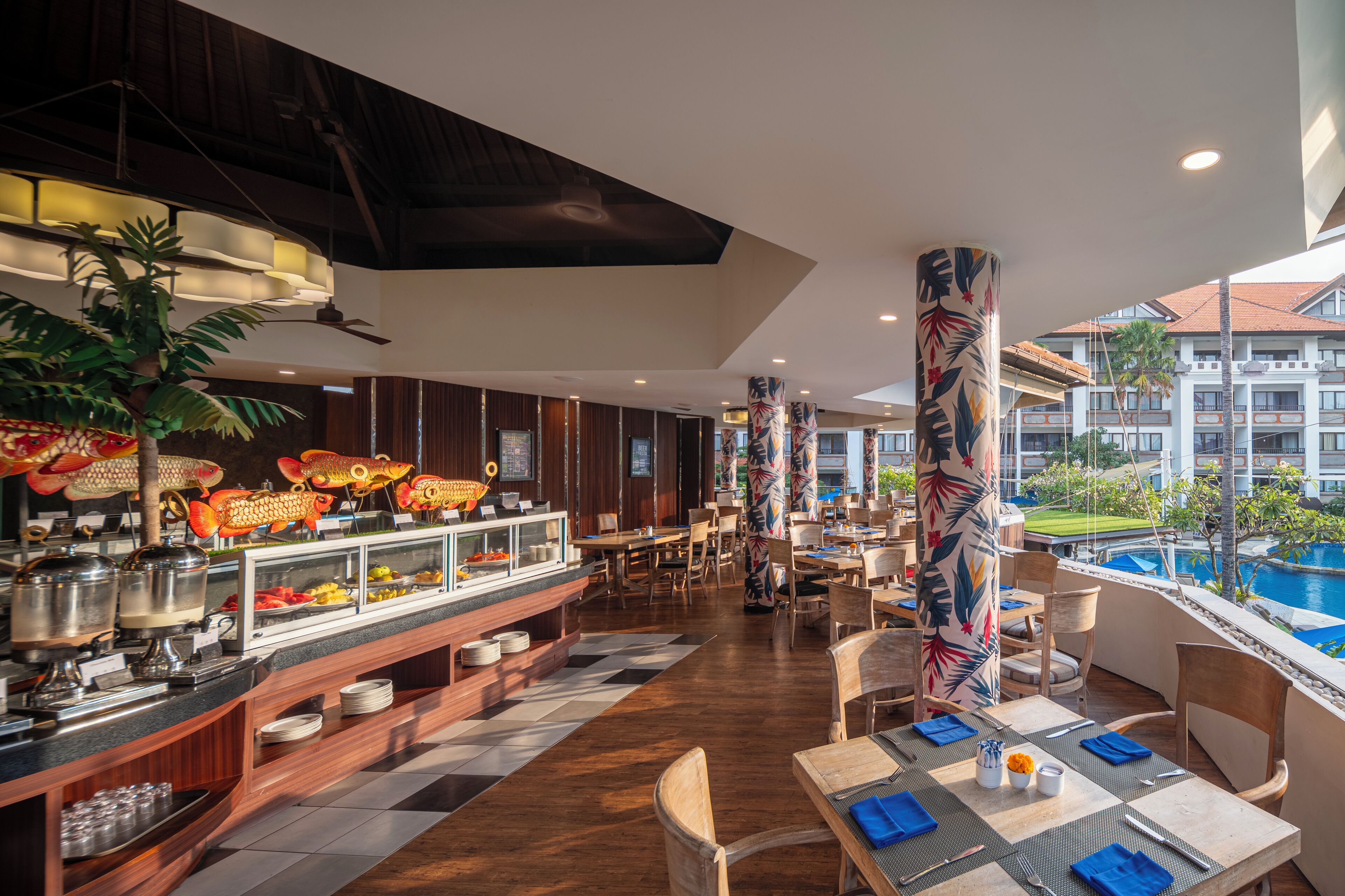 Un restaurante con bufé, suelo de madera y vistas a una piscina y un edificio al fondo.