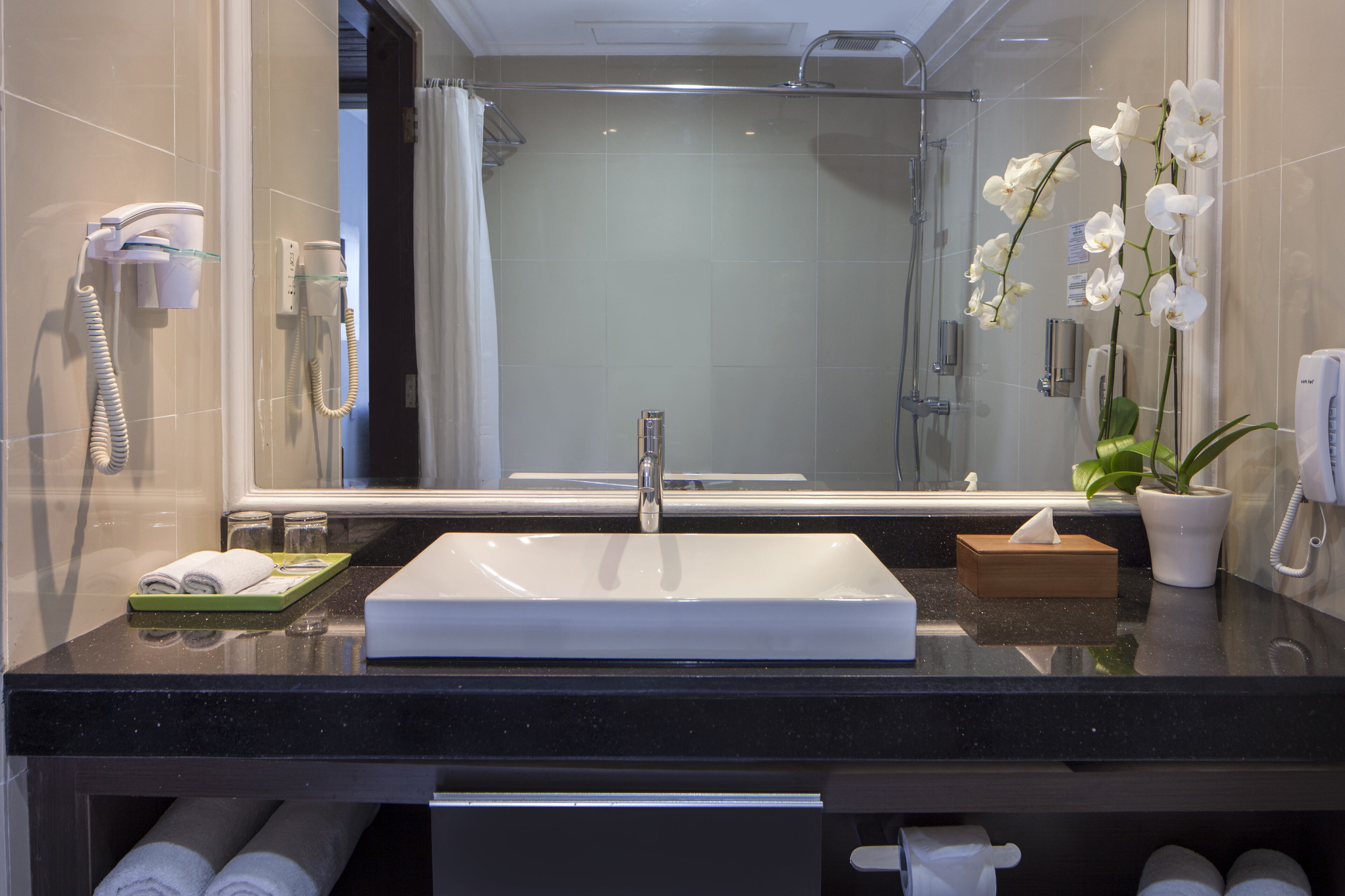 Een moderne badkamer met een grote spiegel, een wastafel, een douche en een telefoon.