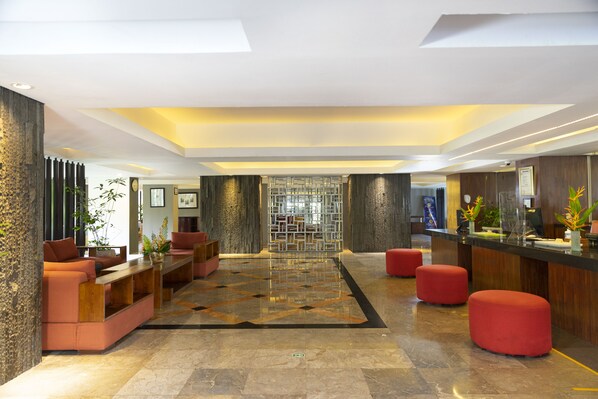 A modern lobby with a reception desk, seating areas, and a decorative wall.