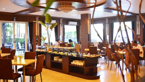 A restaurant with a central buffet area, multiple dining tables, and chairs. - Country Heritage Resort Hotel (Surabaya)