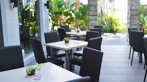 An outdoor café with tables and chairs, surrounded by plants and a stone wall. - Country Heritage Resort Hotel (Surabaya)