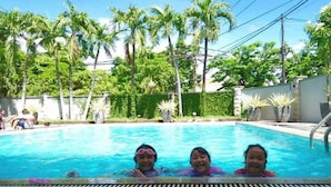 A swimming pool with clear blue water, surrounded by palm trees and greenery. - Country Heritage Resort Hotel (Surabaya)