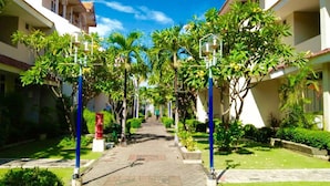 A pathway lined with palm trees and blue street lamps, leading to a building with balconies. - Country Heritage Resort Hotel (Surabaya)