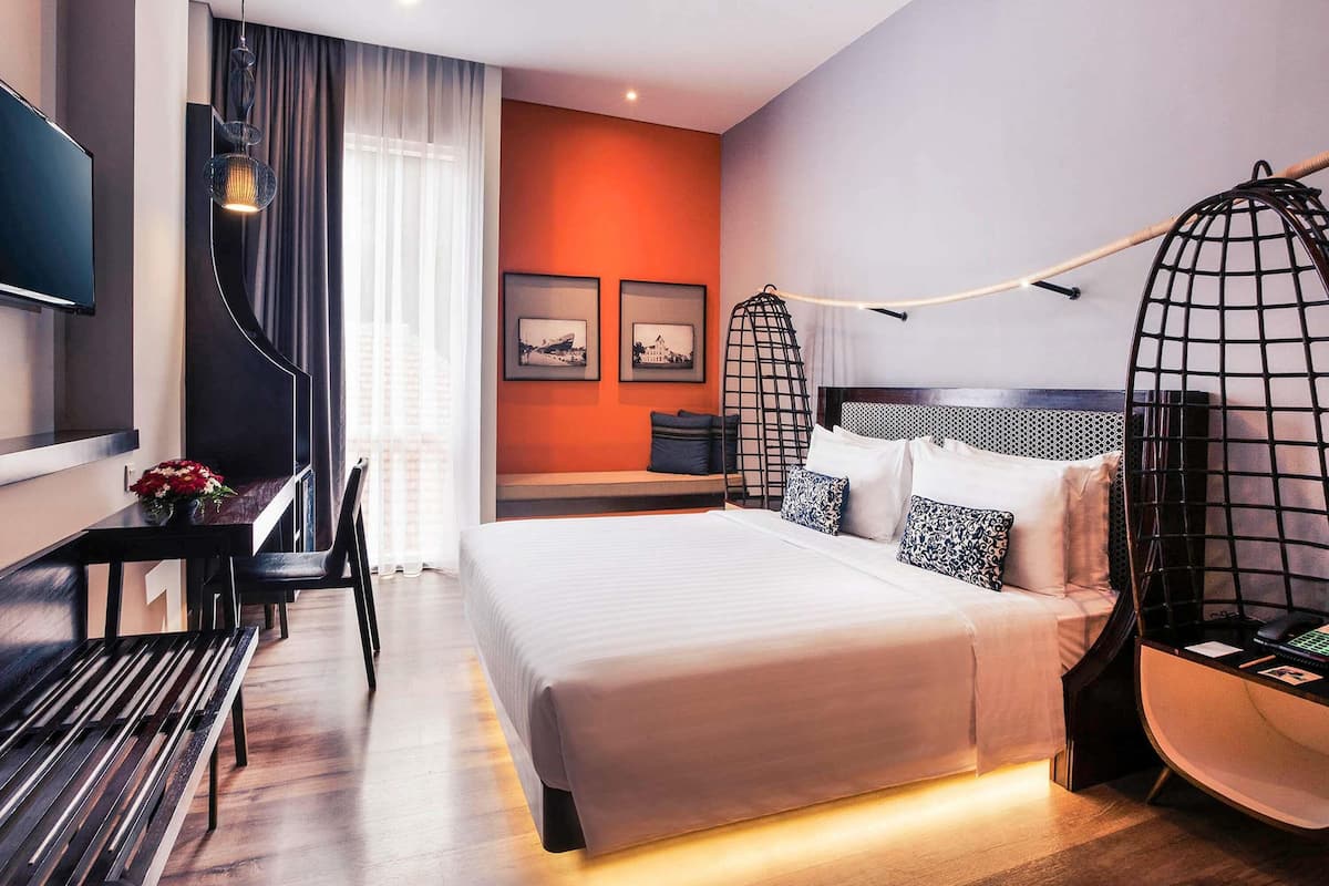 A modern hotel room with a bed, desk, chair, and a TV.