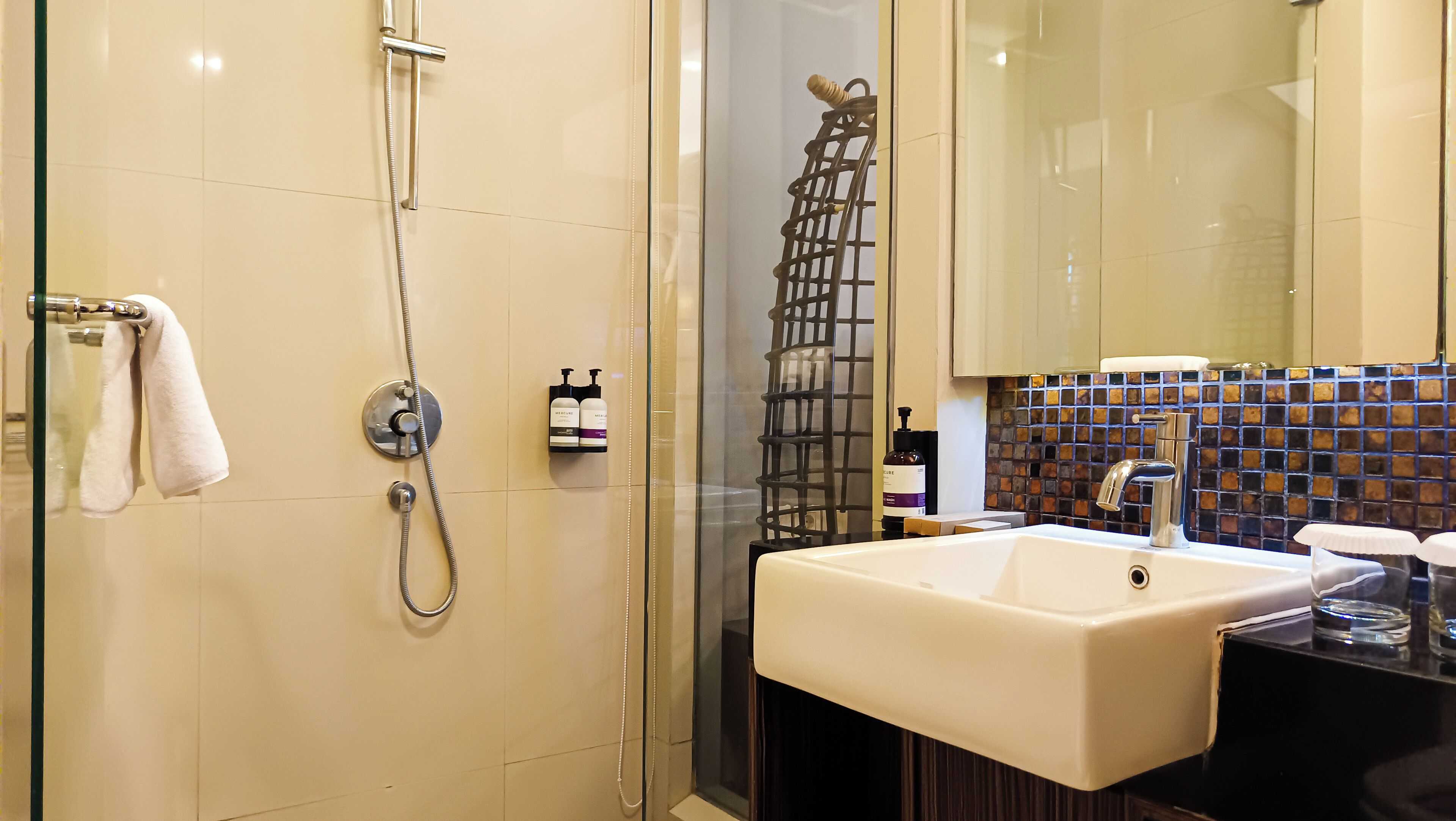 A modern bathroom with a glass-enclosed shower, a white sink, and a tiled backsplash.