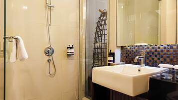 A modern bathroom with a glass-enclosed shower, a white sink, and a tiled backsplash.