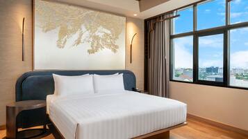 Une chambre d’hôtel moderne avec un grand lit, une vue sur la ville et un élément décoratif mural.
