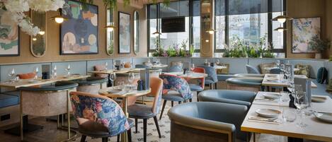 A restaurant interior with booths, tables, hanging plants, and artwork on the walls.