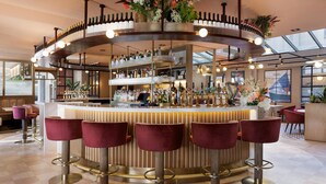 A bar area with a circular bar counter, multiple stools, and a variety of bottles. - Hilton Garden Inn Dublin City Centre (Dublin)