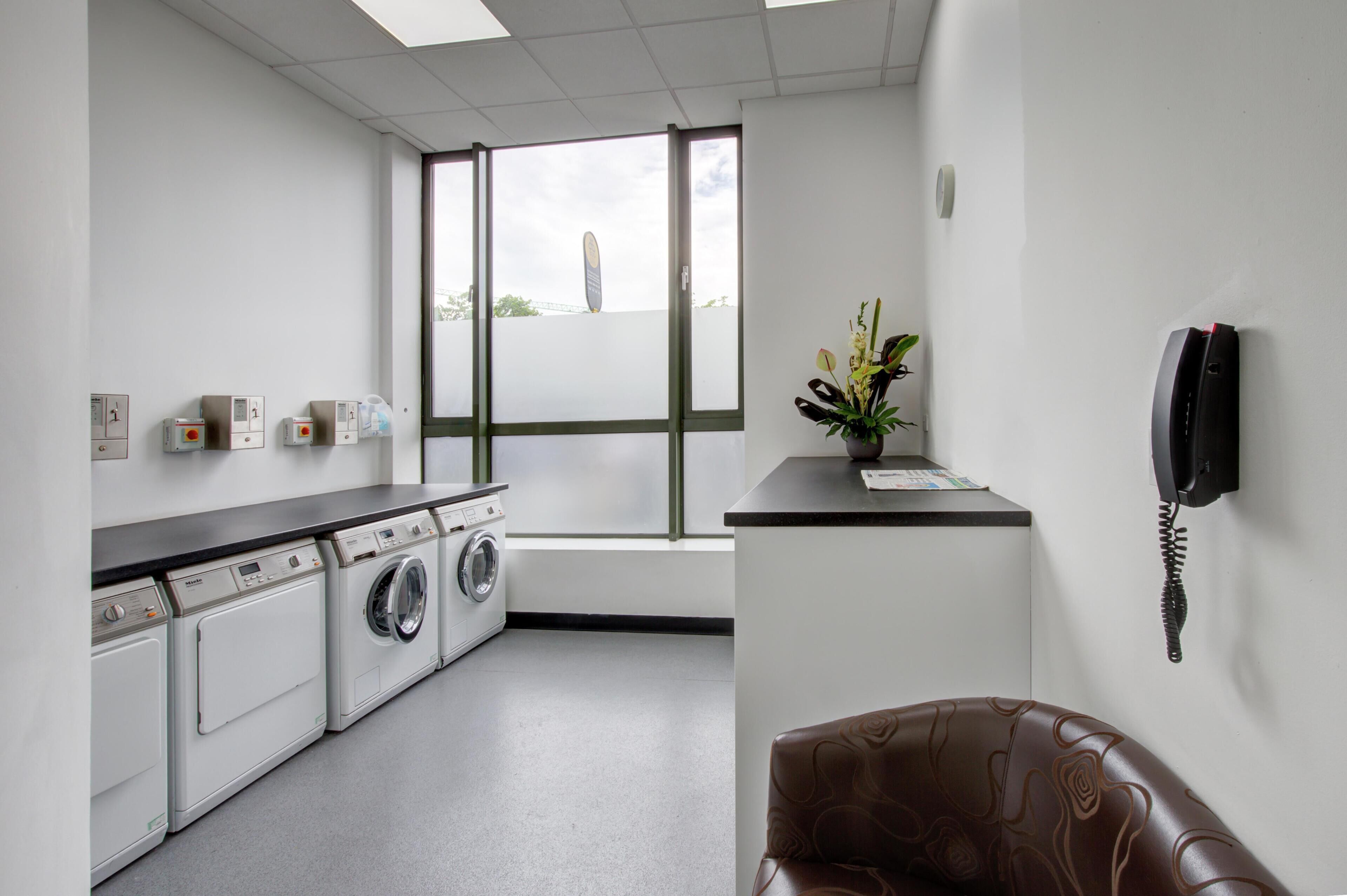 A laundry room with a washing machine, dryer, and a telephone.