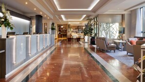 A hotel lobby with a reception desk, seating area, and a view of the interior. - Hilton Garden Inn Dublin City Centre (Dublin)