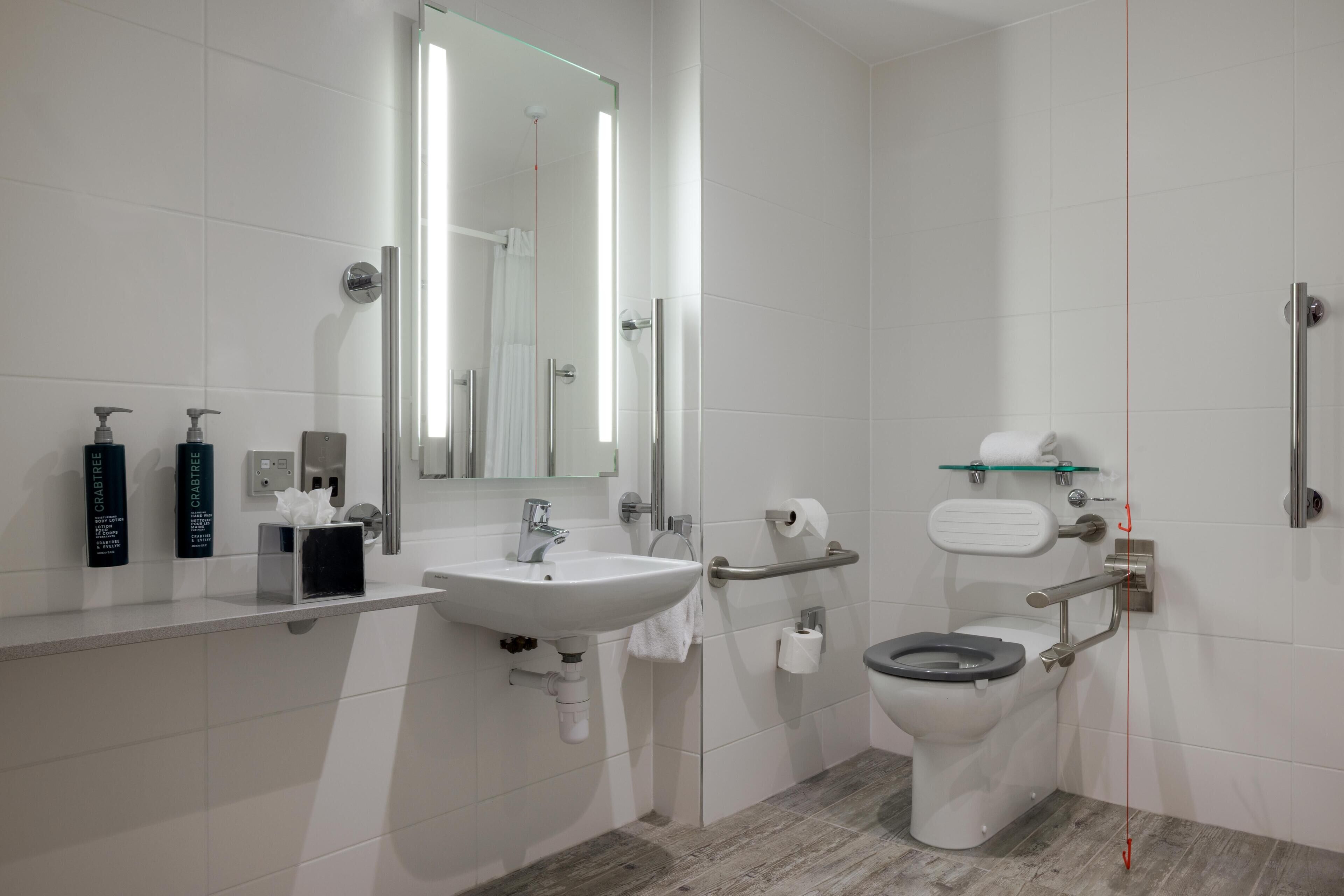 Un baño moderno con lavabo, espejo, inodoro y ducha.
