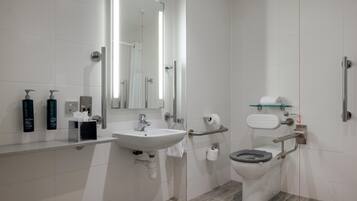 Un baño moderno con lavabo, espejo, inodoro y ducha.