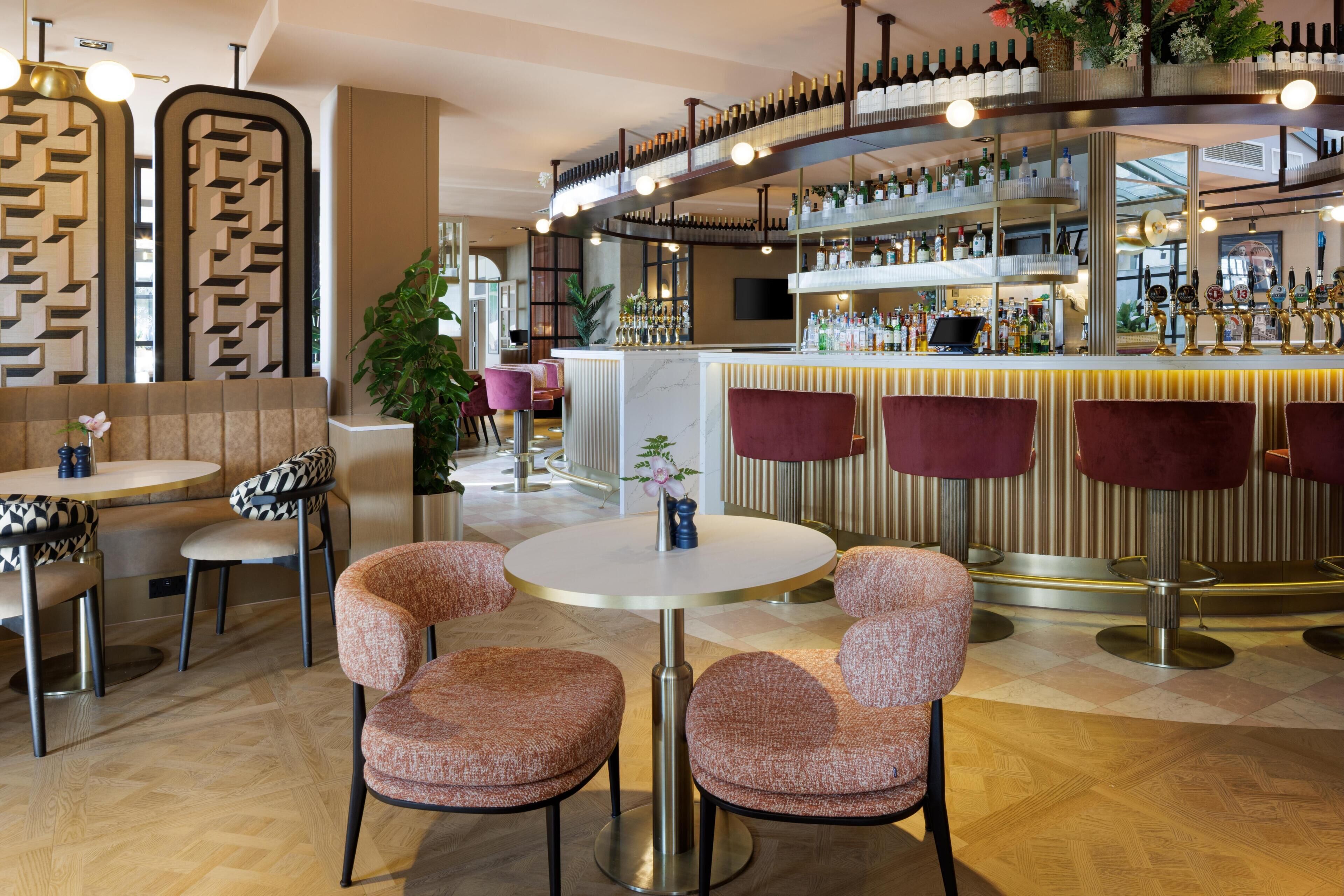 A bar area with multiple seating options, a bar counter, and a variety of bottles and glasses.