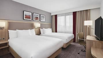 Habitación de hotel con dos camas, televisión, escritorio y silla.