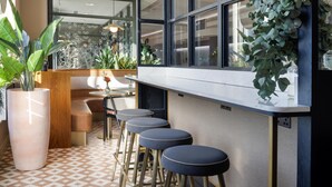 A modern bar area with a counter, stools, and potted plants. - Hilton Garden Inn Dublin City Centre (Dublin)