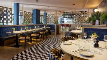 A restaurant with checkered flooring, round tables, and booths.