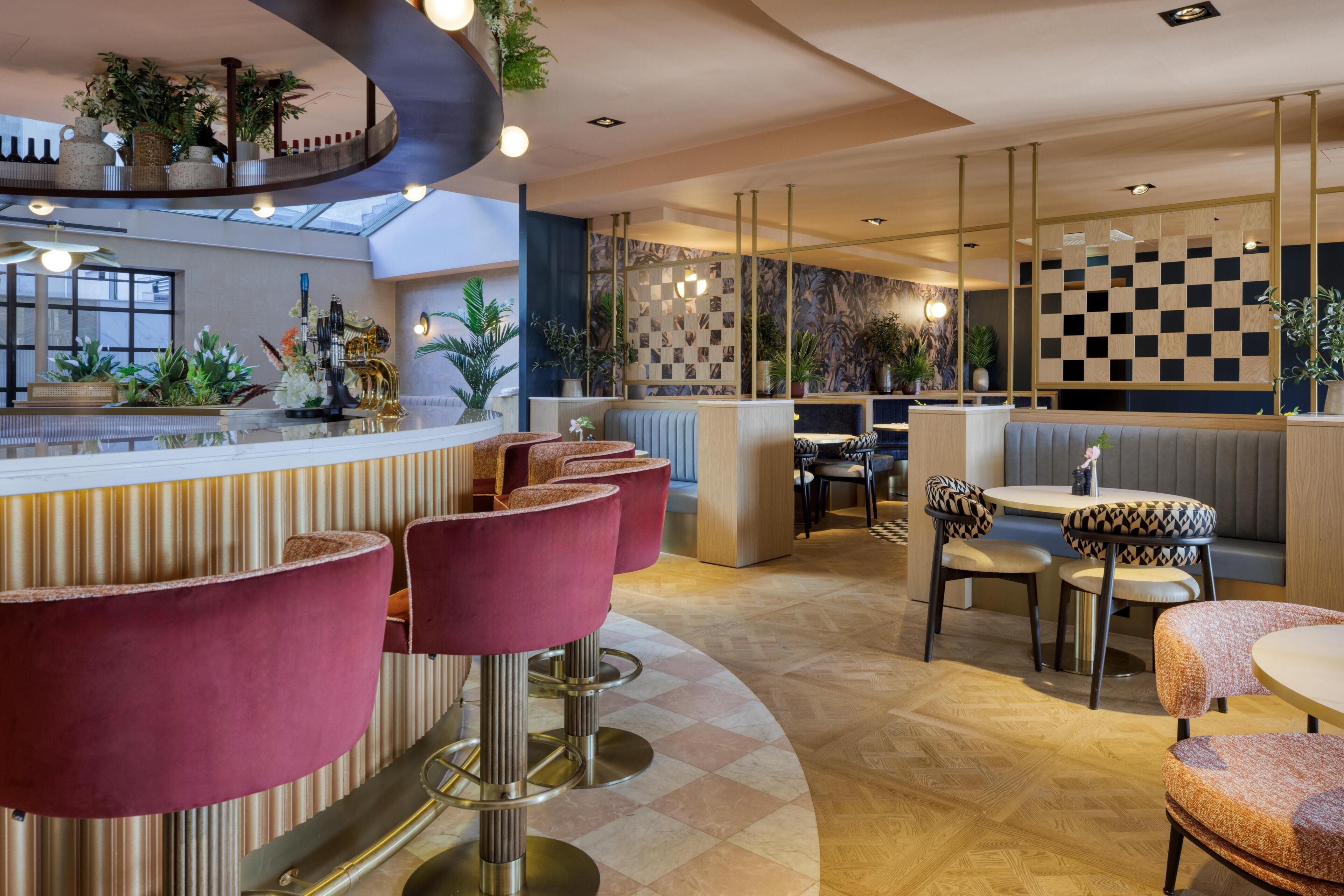 A modern bar area with high stools, a counter, and a seating area with patterned cushions.