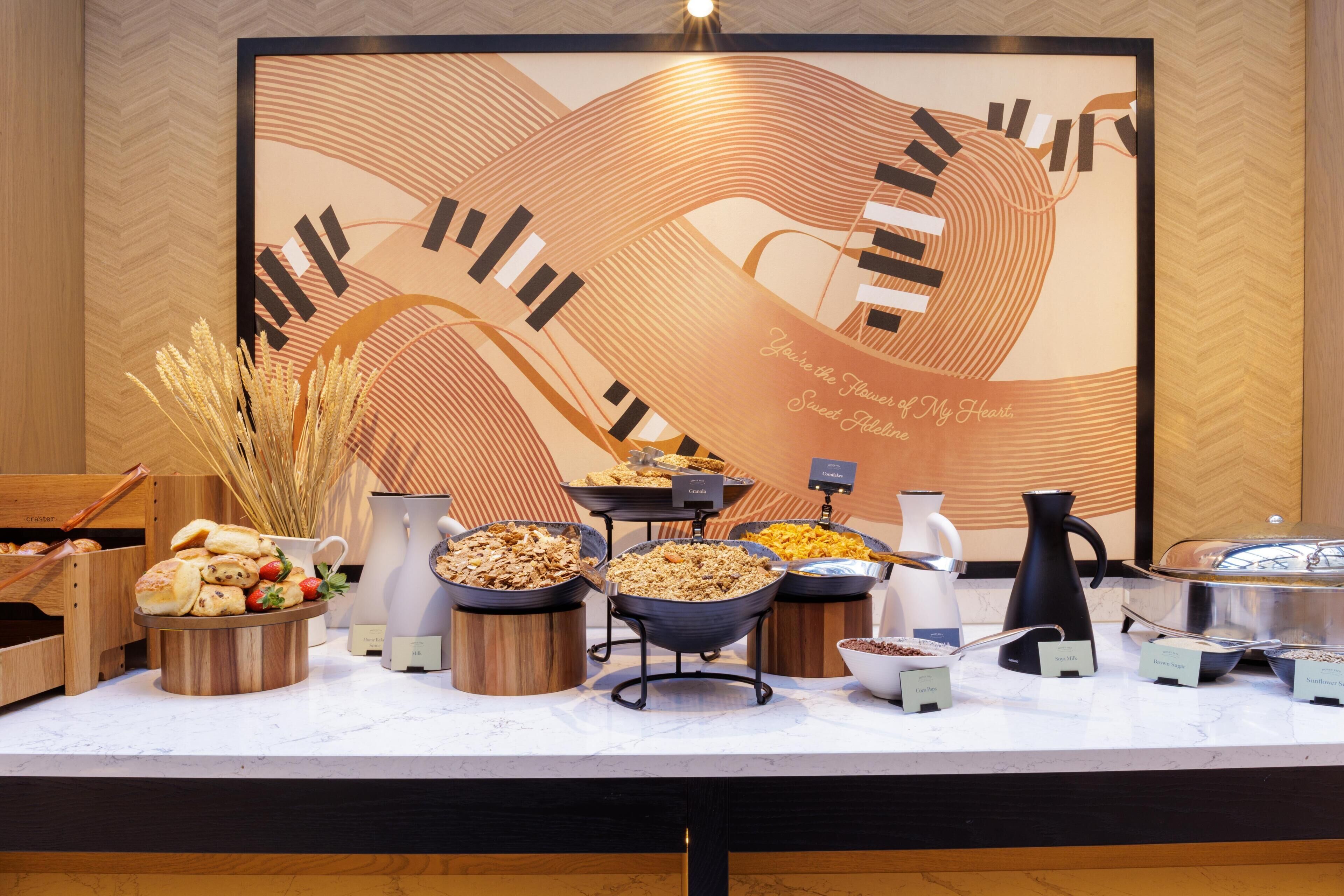 A buffet setup with various food items and a decorative wall in the background.